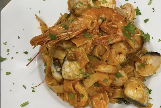 Uno de nuestros platos de pasta: tagliatelle con gambas y almejas en salsa de tomate, con tiras de calabacín y perejil picado por encima.